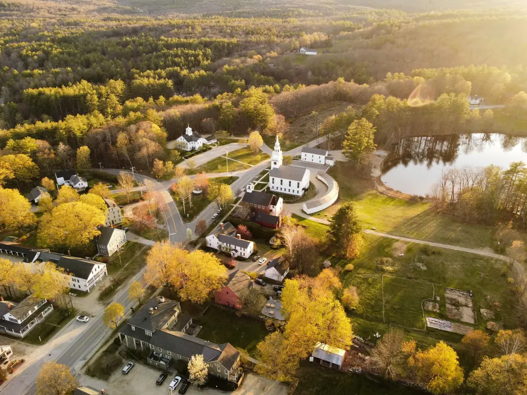 Aerial view of a New England town in fall color with a white church steeple.