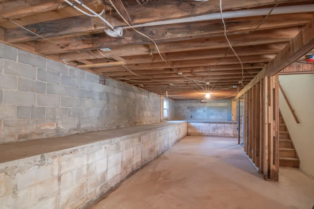 Long unfinished basement with a block foundation and open joists.