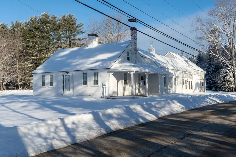 Cape-style New England house with snowbanks along the road.