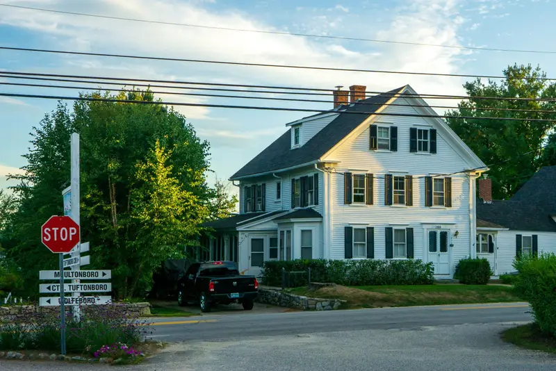 White New England colonial with a lawn and a quiet road.