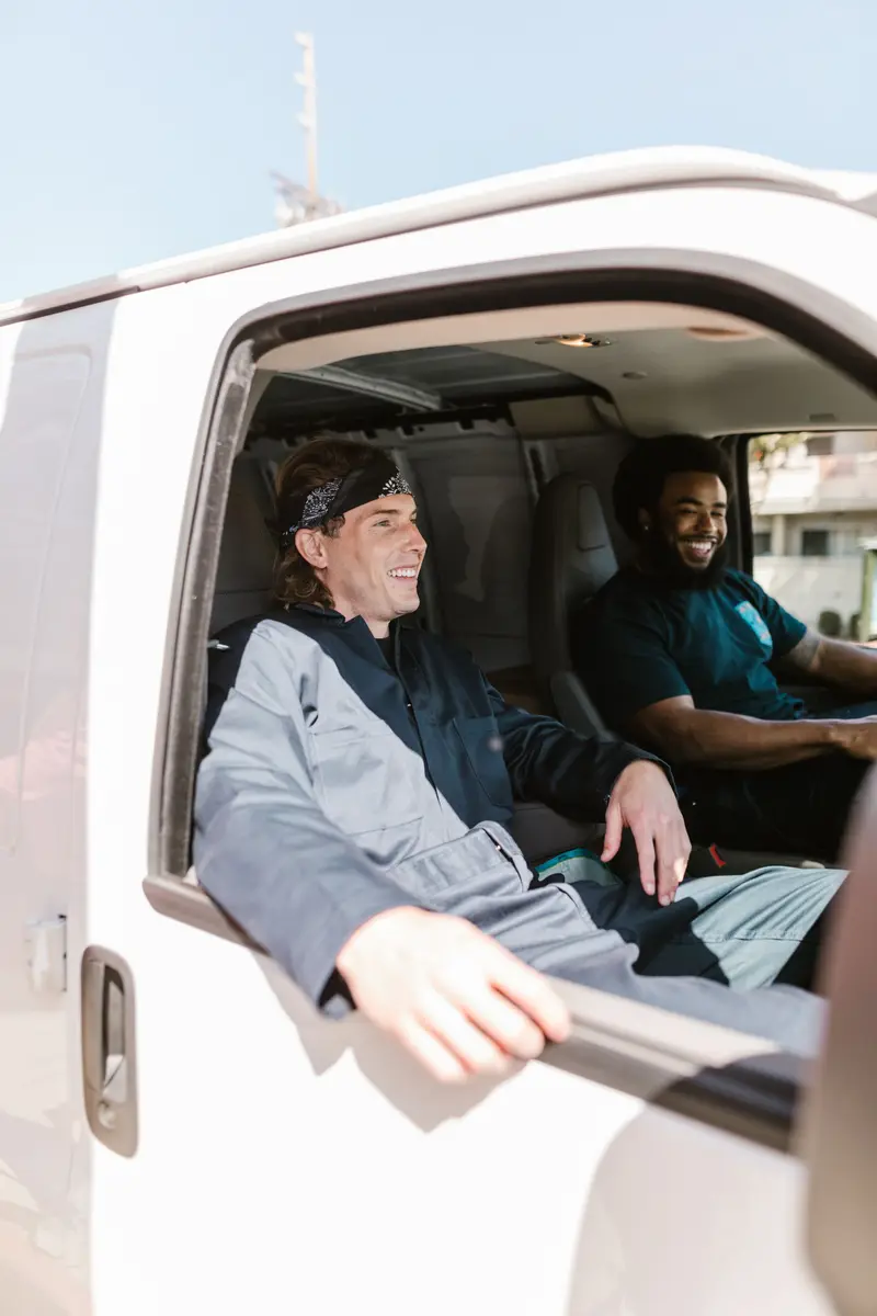 Two crew members in the cab of a white van, heading to the next call.