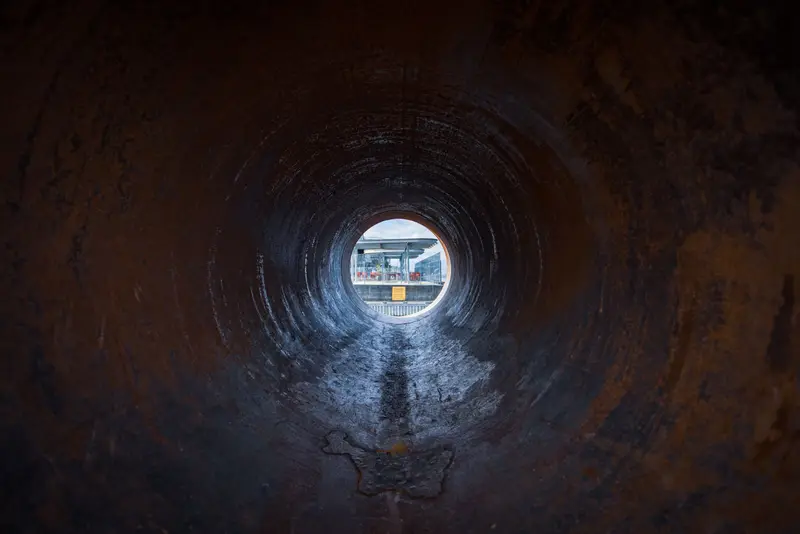 Camera view looking down the inside of a sewer pipe.