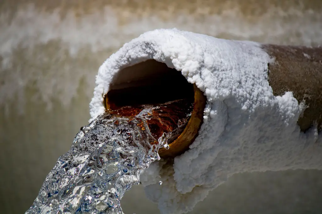 Water blasting out of a frost-covered pipe in winter.