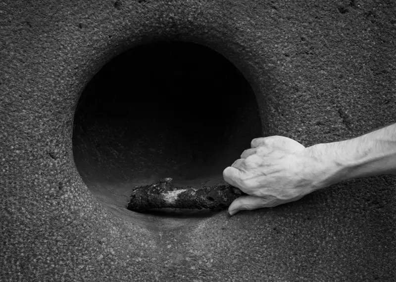 Gloved hand reaching into the open end of a large pipe.