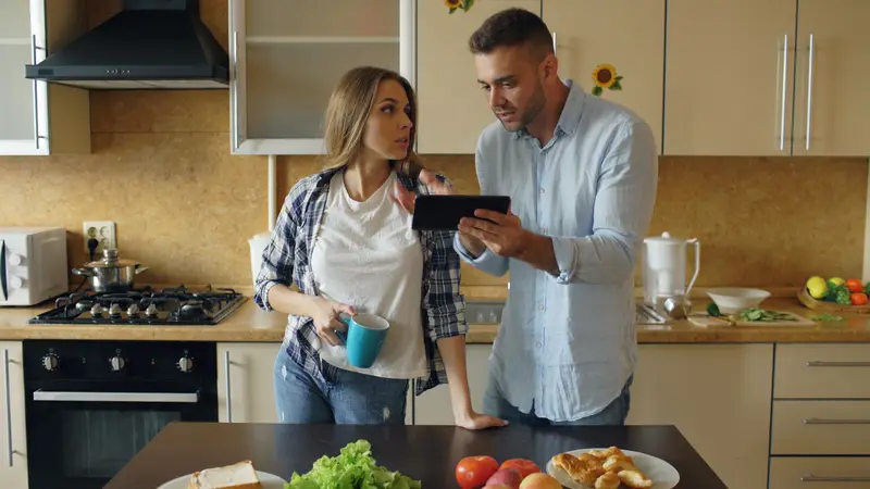 Technician showing a homeowner something on a tablet in her kitchen.