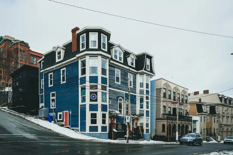 Tall New England multi-family house on a snowy city street.